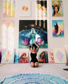 a woman sitting on the floor in front of paintings