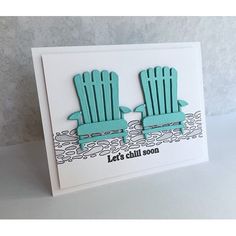 a card with two lawn chairs sitting on the beach, one is blue and the other is green