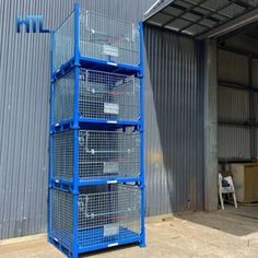 three blue metal containers stacked on top of each other in front of a warehouse door