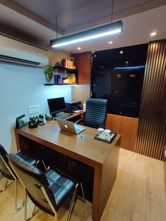 a wooden desk topped with two laptops next to a wall mounted air conditioner