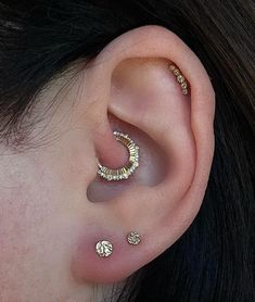 a close up of a person's ear with three different piercings on it