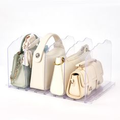 four purses are in a clear display case on a white background with no one around them