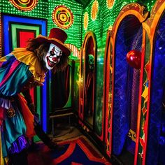 a creepy clown is standing in front of some brightly colored mirrors and doors with lights on them