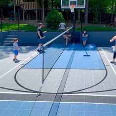 people playing basketball on an outdoor court with net in the foreground and trees in the background