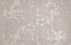 an area rug with white flowers on grey ground and light gray wallpaper in the background