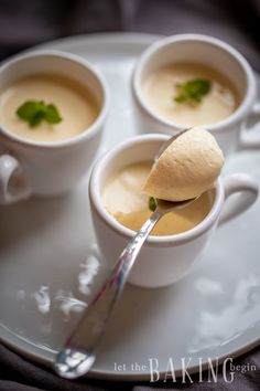 three white cups filled with soup on top of a plate