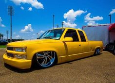 a yellow pickup truck parked in a parking lot next to a red and white trailer