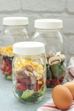 three mason jars filled with food sitting on top of a counter next to an egg