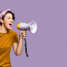 a woman holding a yellow and white megaphone in front of her face while screaming