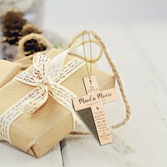 two wrapped presents tied with twine on top of each other, next to a pine cone