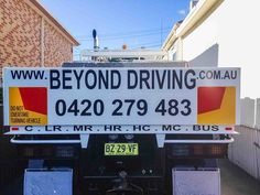 the back end of a truck that is parked in front of a building with a sign reading beyond driving