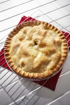 a pie sitting on top of a metal rack next to a red napkin and cooling rack