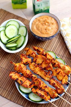 grilled chicken skewers with cucumbers and sauce on a bamboo mat