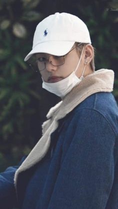 a woman wearing a white hat and neck gaiter holding a cell phone in her hand