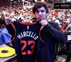 a man holding up a jersey at a basketball game