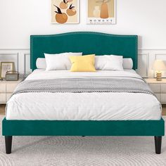 a bed with white sheets and green headboard next to two pictures on the wall