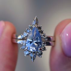 a person holding a ring with a large blue diamond in it's middle finger