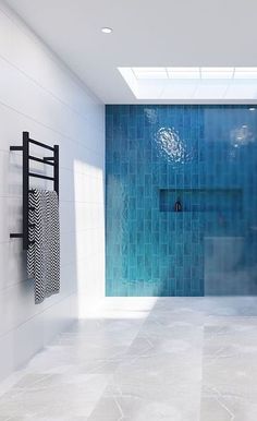 a bathroom with blue tile walls and flooring next to a white bath tub under a skylight