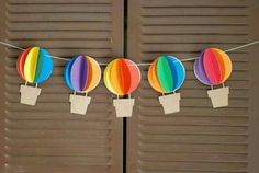 several colorful hot air balloons hanging from clothes pins on a line with paper tags attached to them