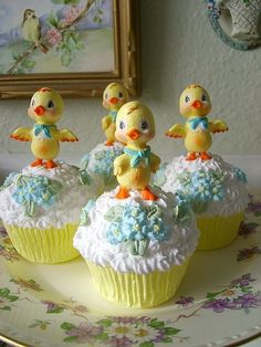 four cupcakes decorated with yellow and blue icing, sitting on a plate