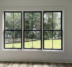 an empty room with three windows and wood flooring