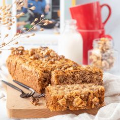 two slices of granola bread on a wooden cutting board next to a glass of milk