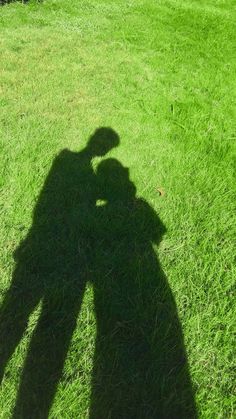 the shadow of a person standing on top of a lush green field