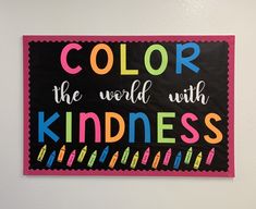 a sign that says, color the world with kindness on it's side in front of a white wall