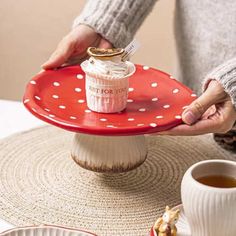 a person holding a red plate with a cup on it