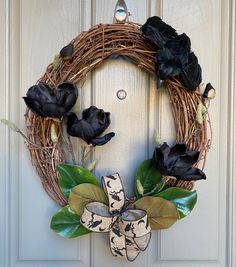 a wreath with black flowers is hanging on a door