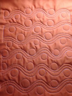 a close up of a quilted piece of fabric with waves on the front and back