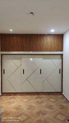 an empty room with wooden flooring and white cupboards on the wall behind them