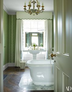 a bath tub sitting next to a white sink in a bathroom under a chandelier