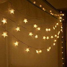 a string of stars is hanging from the side of a window with lights on it