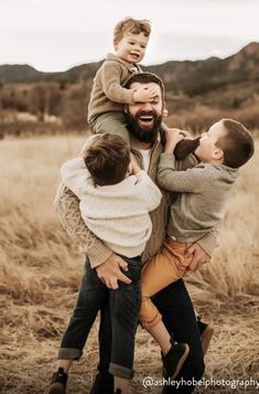 a man is holding two boys in his arms and the boy is on top of him