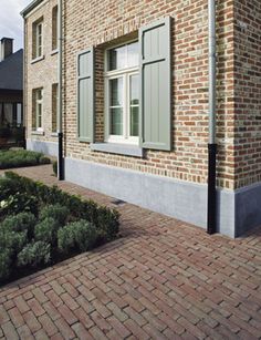 a brick building with green shutters on the windows