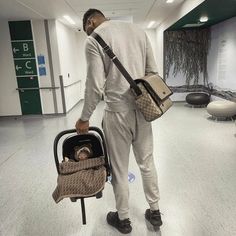 a man is holding a baby in a stroller and looking down at the ground