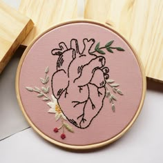 an embroidered heart on a pink background with flowers and leaves in the hoop next to wooden blocks