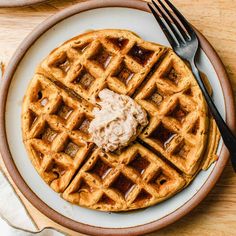 a plate with waffles and butter on it, next to a knife and fork