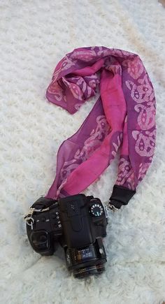 a camera and scarf laying on top of a bed