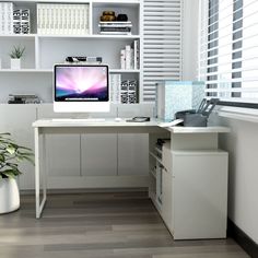 a desk with a computer on top of it next to a plant and bookshelf