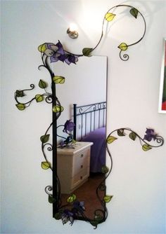 a mirror with vines and flowers on it in the corner of a room next to a dresser