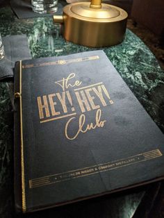 the hey hey club book is sitting on top of a green table with gold lettering