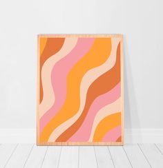 an orange, pink and yellow abstract painting on a wooden frame in a white room