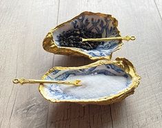 two small bowls with gold handles are sitting on a wooden surface, one is filled with seaweed and the other has black seeds in it