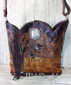 I call this style of cowboy boot purse my “Top Shelf” boot purse because it is so much more than a double boot purse. I craft a layer or more of leather or hides onto the basic boot purse design and add a little hand-cut fringe to offer you something truly original. This western leather purse is roomy, tote-style with original boot interior, without pockets. Measures 12.5"Hx14"W. With a 41" strap. Approx 2 lbs. Some purses have scuffs, irregularities or defects from the boot factory. This ads to Western Style Bags With Fringe For Everyday Use, Totes Boots, Best Cowboy Boots, Fringe Cowboy Boots, Fringe Western Purse, Cowboy Boot Purse, Hipster Purse, Statement Purse, Brown Western Bag With Fringe