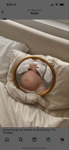 an image of a baby in a round mirror on a bed with white linens