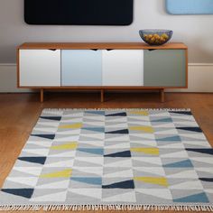 a living room area with a rug, television stand and painting on the wall above it