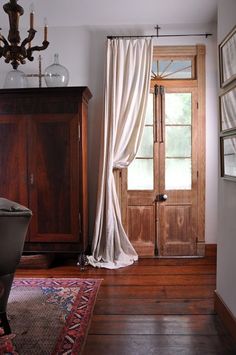 a room with a wooden door and white curtains