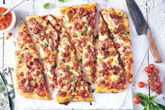 several slices of pizza sitting on top of a white napkin next to a knife and some tomatoes